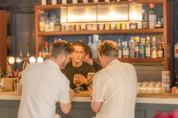 Atmospheric restaurant bar counter shoot location in Streatham Hill, South West London SW16 featuring customers sitting at the bar being served drinks by a bartender under warm modern lighting, the ultimate high-conversion backdrop for beverage advertising, lifestyle brand campaigns, and casual dining commercial filming via Love Locations.