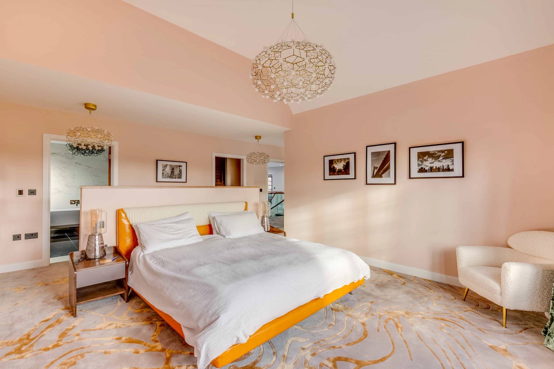 Blush pink master bedroom featuring a white bed, abstract art prints, and gold chandelier, Love Locations CB2.