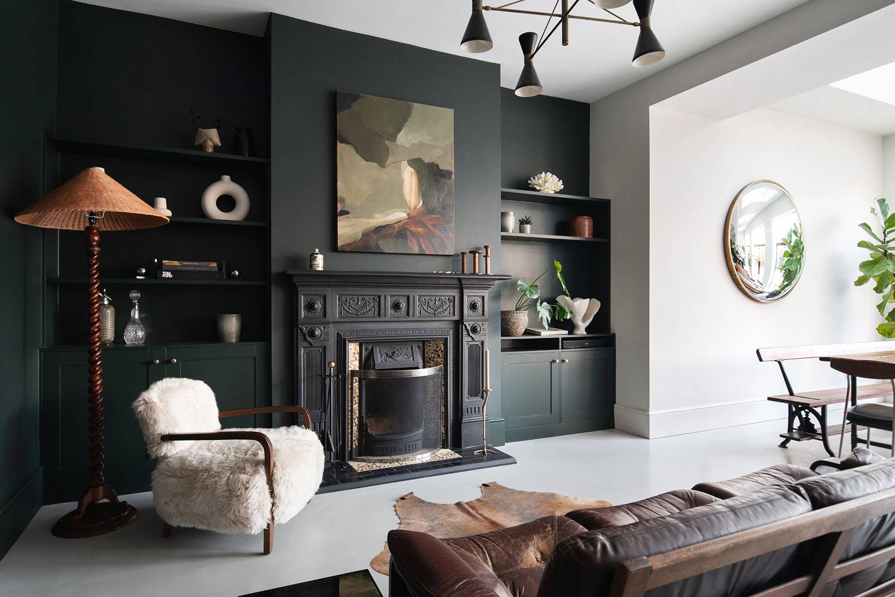 Moody living room with dark green walls, cast iron fireplace surround, abstract artwork, and plush seating, ideal for drama filming, Love Locations SW16.