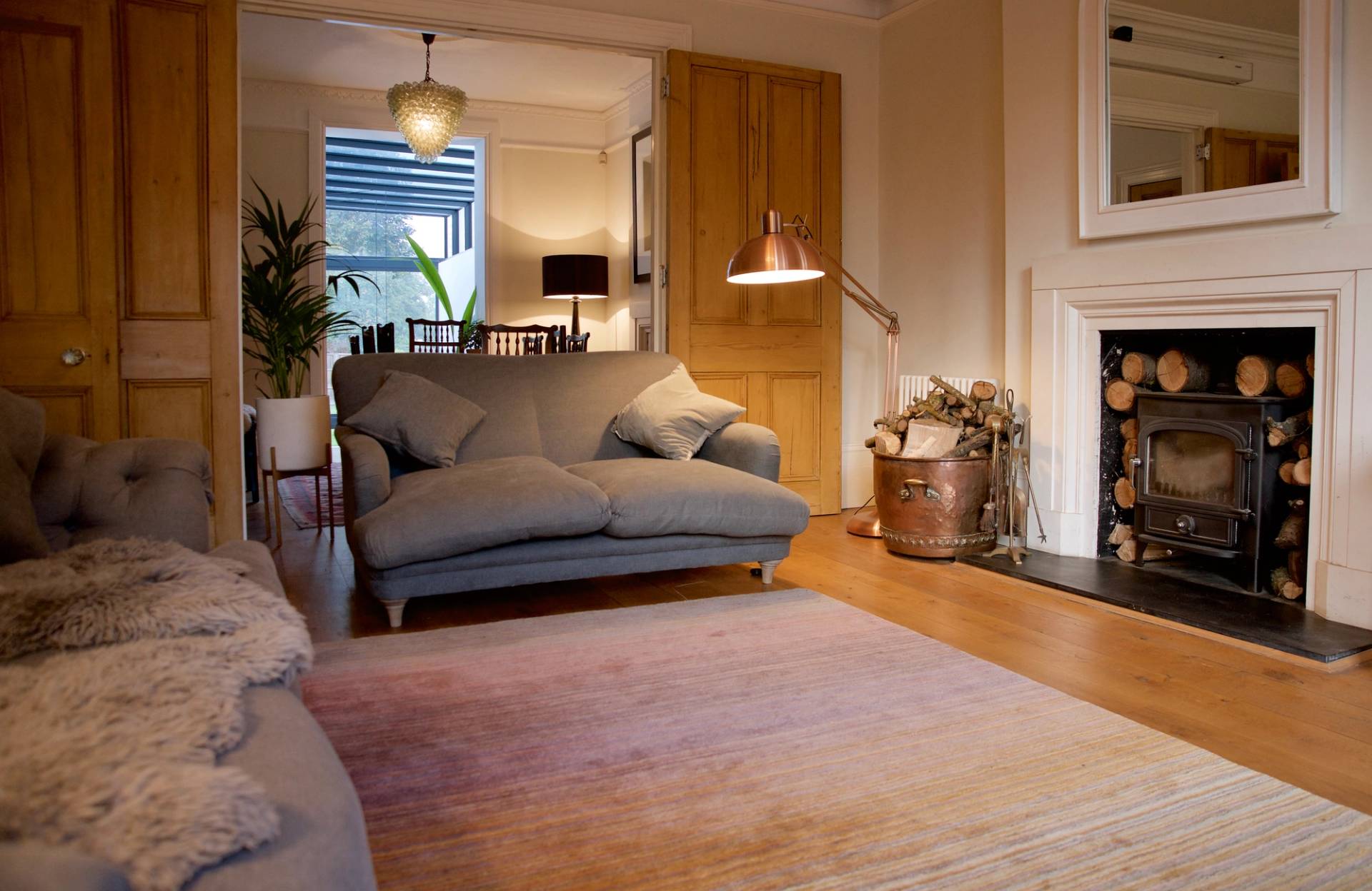 Cozy period reception room featuring a grey sofa, fireplace, and soft pastels rug on wood floors, Love Locations TW1.