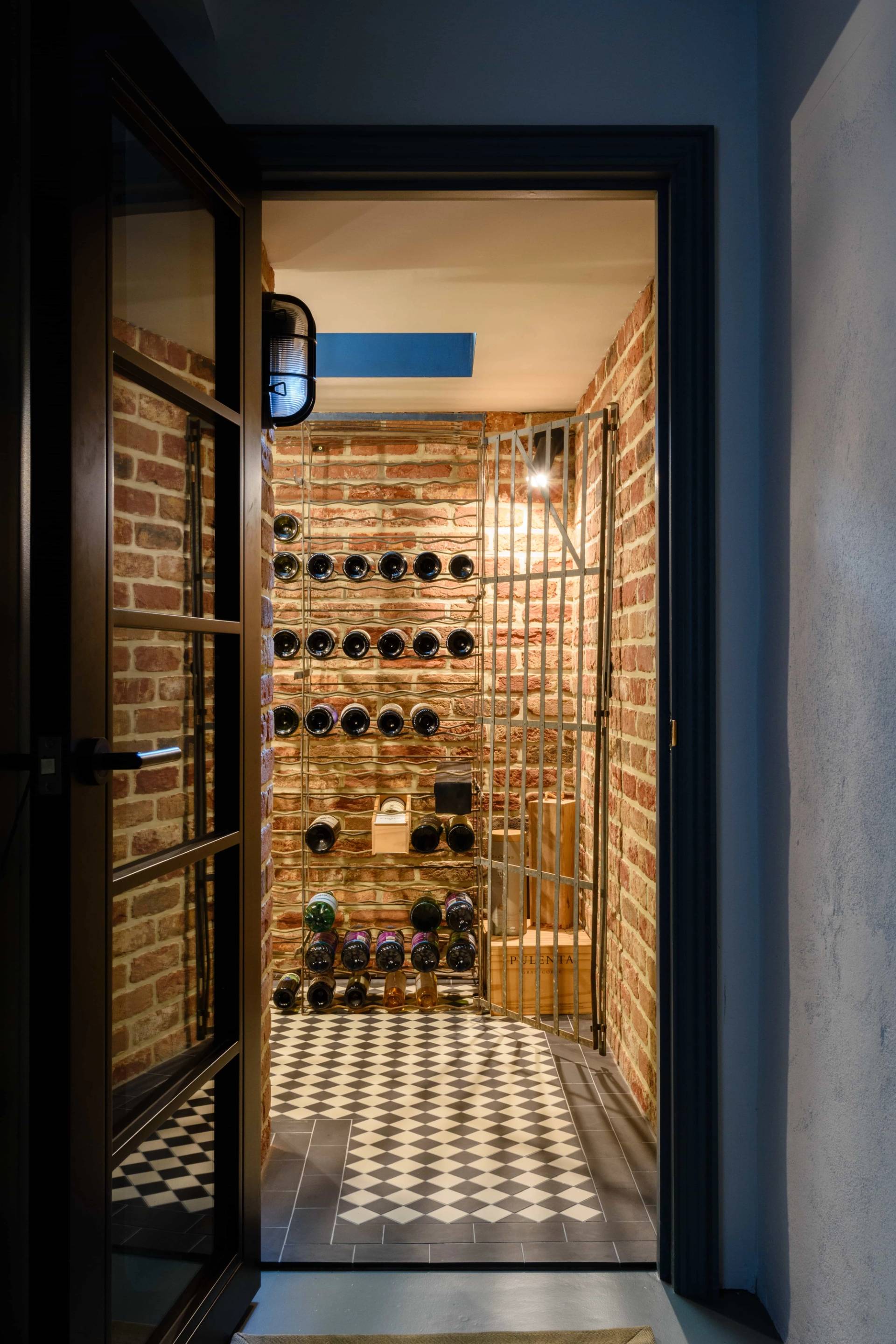 Subterranean brick wine cellar with custom bottle rack storage set behind a glass door, Love Locations TW11.