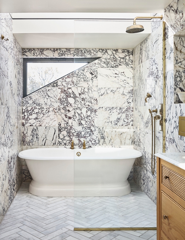 Luxury master bathroom featuring a white freestanding bathtub set against dramatic grey-veined marble walls, Love Locations SE21.