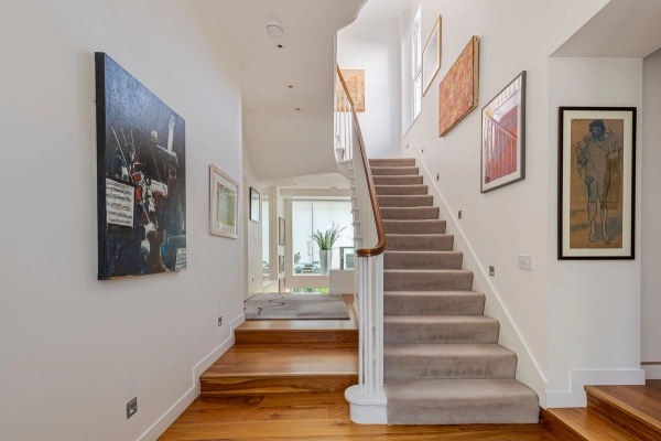 Traditional residential carpeted staircase framed by bright white walls and contemporary artwork, suitable for realistic domestic film scenes, Love Locations.