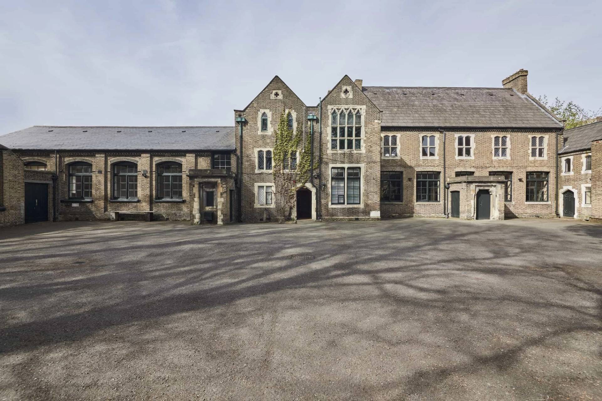 Expansive private paved courtyard exterior hero view set in front of historic stone school buildings in Shoreditch, E2, ideal for outdoor events and automotive filming, Love Locations.