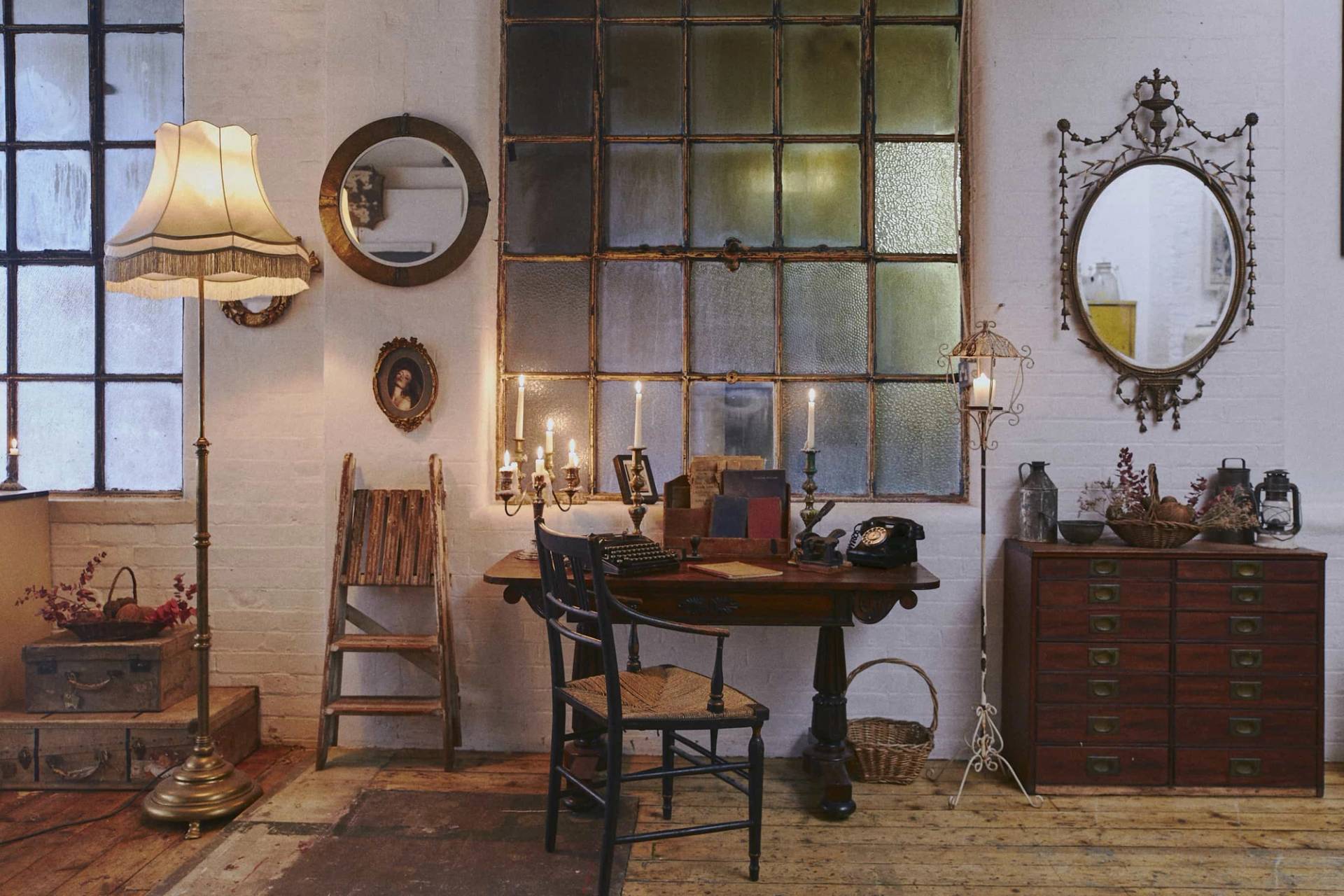 Candlelit antique wooden desk and chair setup against a grid of industrial factory windows, ideal for period drama filming via Love Locations.
