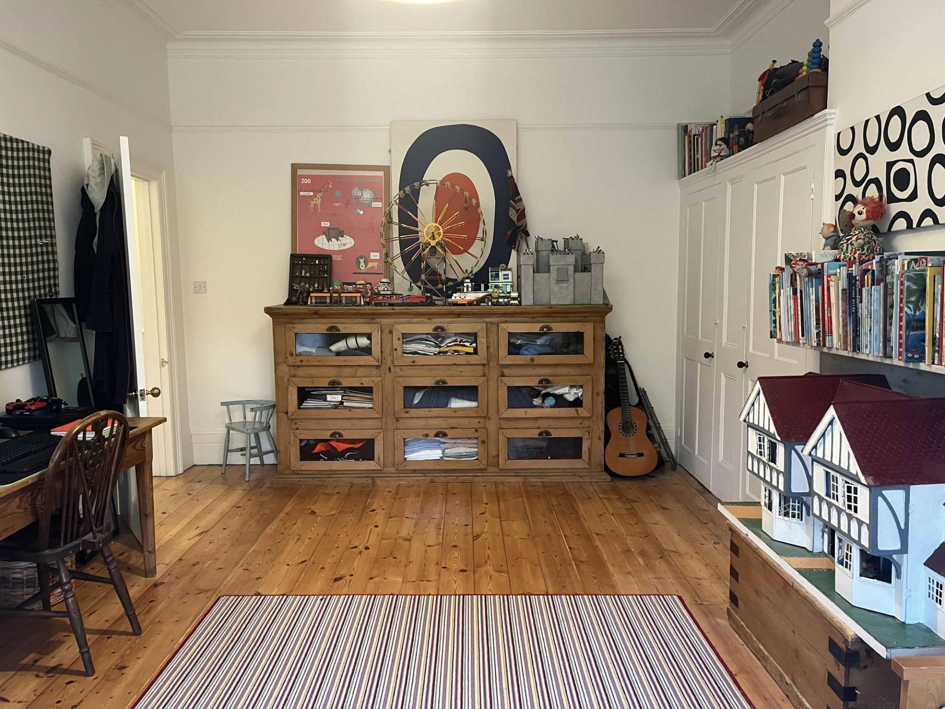 Bedroom storage corner featuring a mid-century glass-front display cabinet, guitar, and striped area rug, Love Locations SE5.