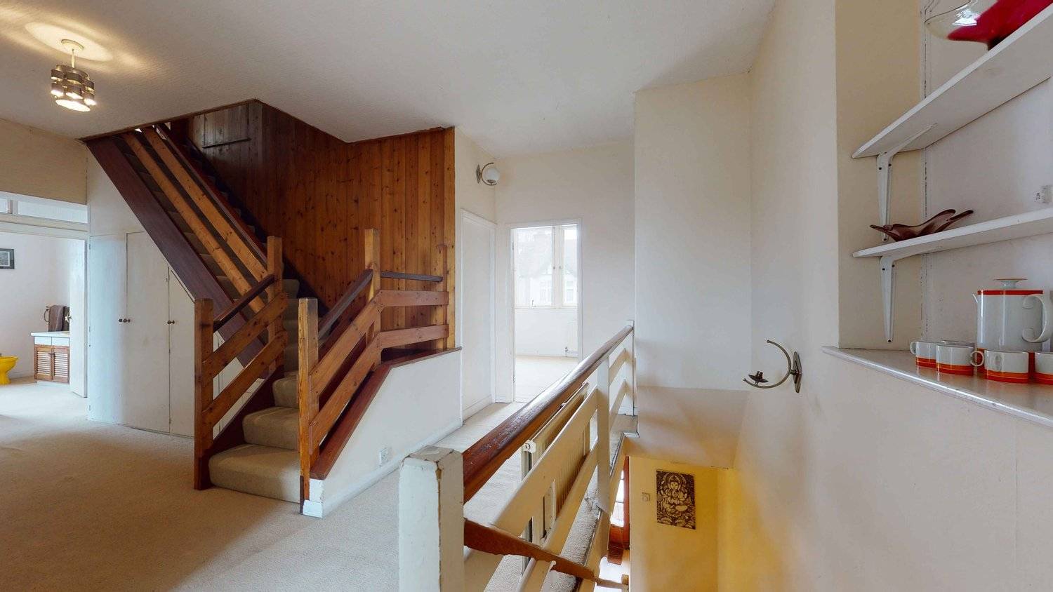 Upper floor landing featuring retro timber stair railings, wood-panelled walls, and original 1970s light fixtures, Love Locations SW16.