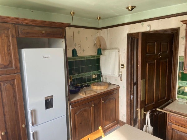 Cozy kitchen breakfast corner featuring a white refrigerator and hanging pendant green lights, suitable for atmospheric lifestyle branding, Love Locations.