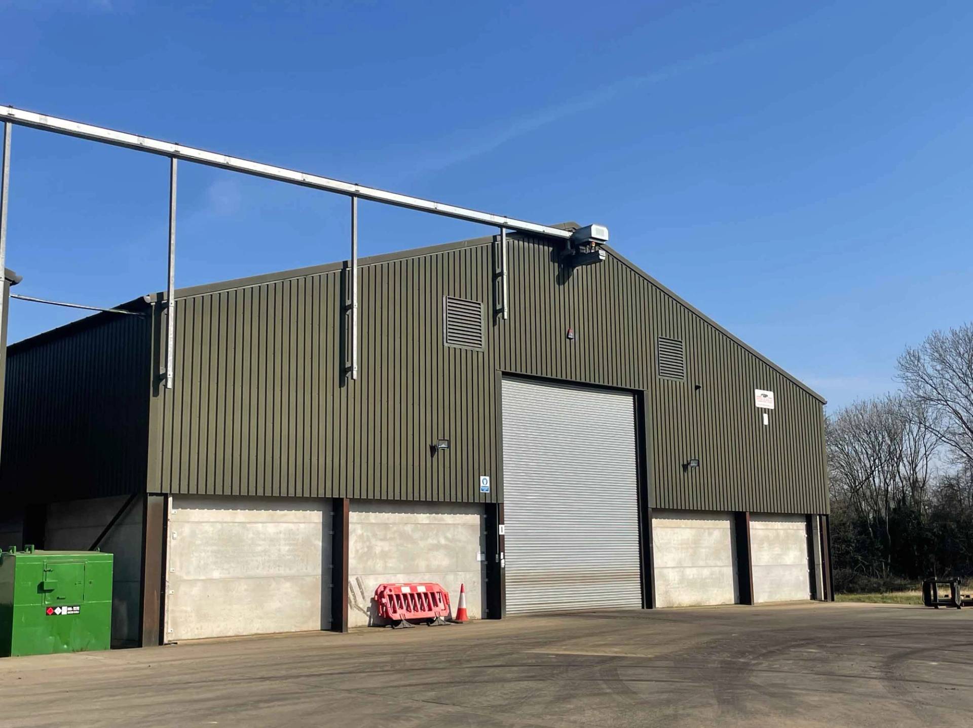 Contemporary industrial farm building with secure roller shutter loading bays, perfect for commercial media production crews, Love Locations NN17.