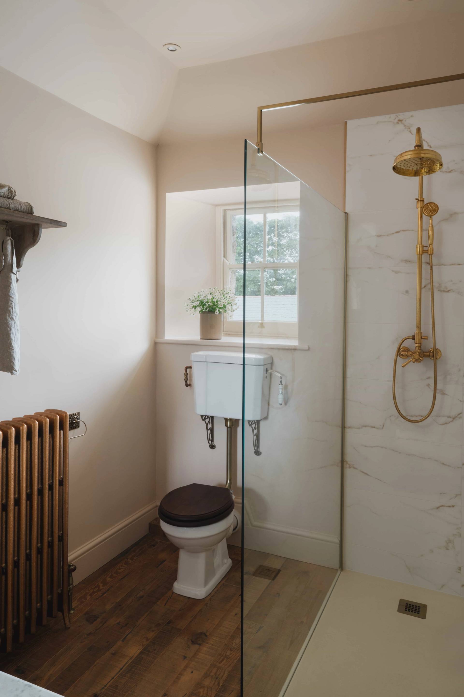 Neutral guest bathroom with a high-tank toilet and gold shower fittings in a Cornish manor through Love Locations.