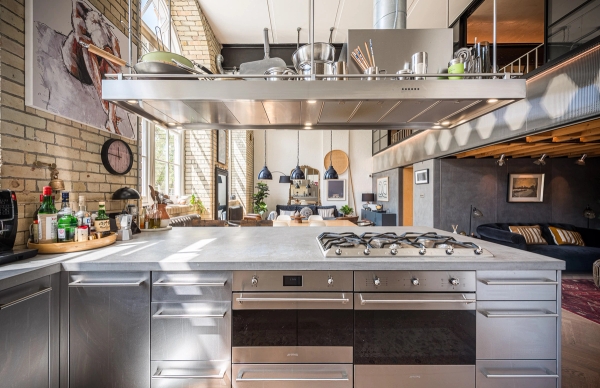 Sleek stainless steel island counter inside a daylit school house conversion available for media hire, Love Locations SE1.