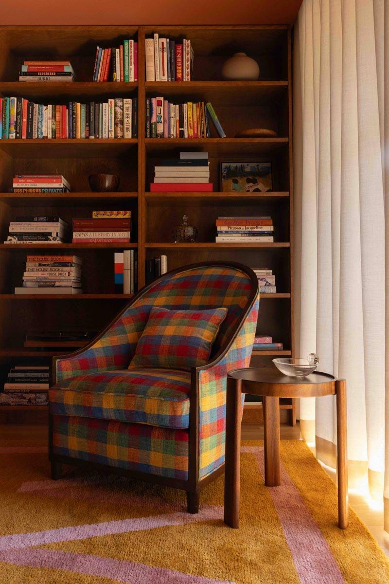 Warm library and reading room location house in Boerum Hill Brooklyn through Love Locations, featuring floor-to-ceiling wooden bookshelves and a plaid tartan armchair.