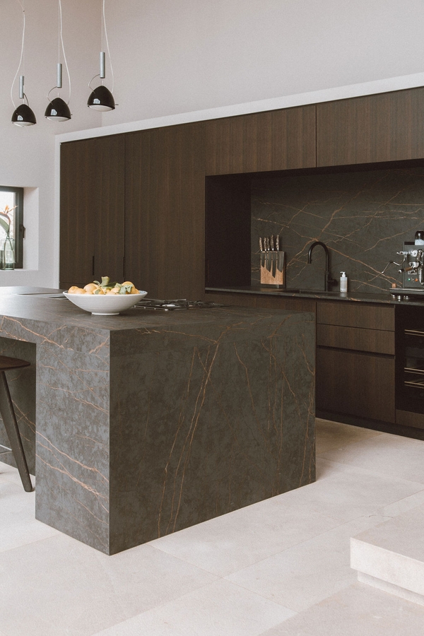 Sleek dark stone kitchen island prep area set in a contemporary luxury Mediterranean villa, Love Locations 07630.