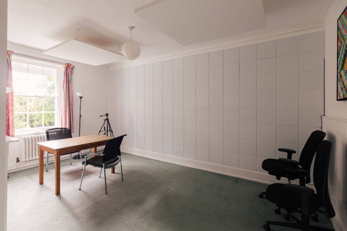 Minimalist white studio room featuring vertical wood slat wall panelling and grey carpet, ideal for video content creation, Love Locations.