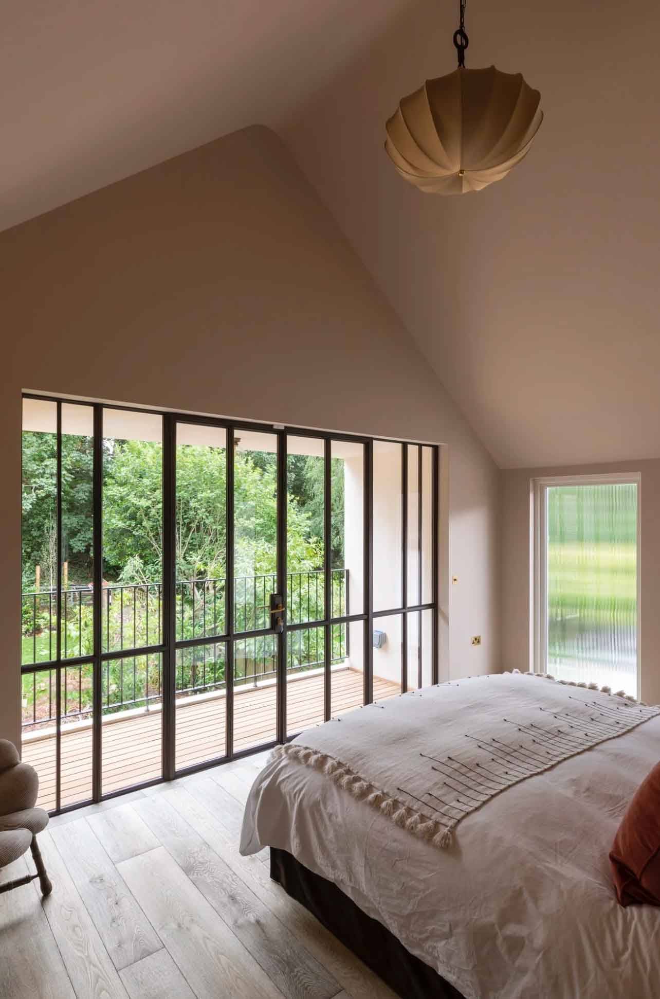 Vaulted master bedroom suite with full-height crittall balcony doors framing garden views, perfect for mattress and sleepwear brand advertising, Love Locations N6.