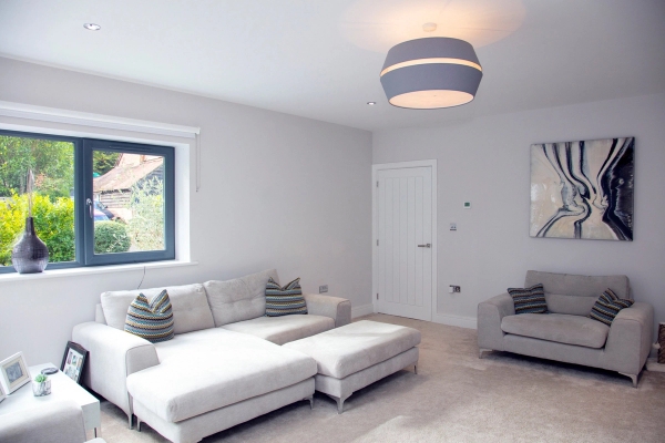 Cozy modern snug room location featuring neutral grey carpets and a plush L-shaped sectional sofa for domestic TV sets, Love Locations.
