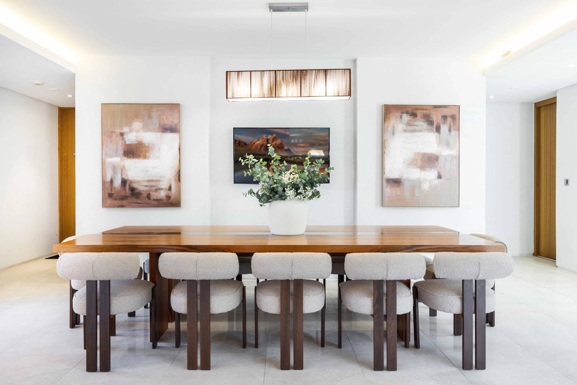 Formal dining space with a solid wood table, beige upholstered chairs, and contemporary art prints, Love Locations WD7.