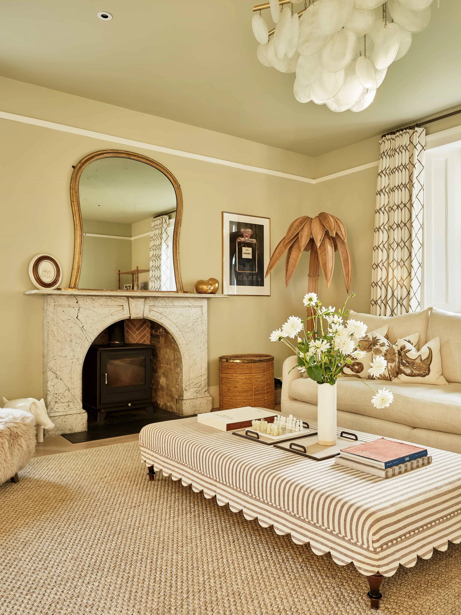 Cozy country lounge featuring a stone fireplace hearth, log burner, gold mirror, and striped ottoman, ideal for autumn apparel shoots, Love Locations.