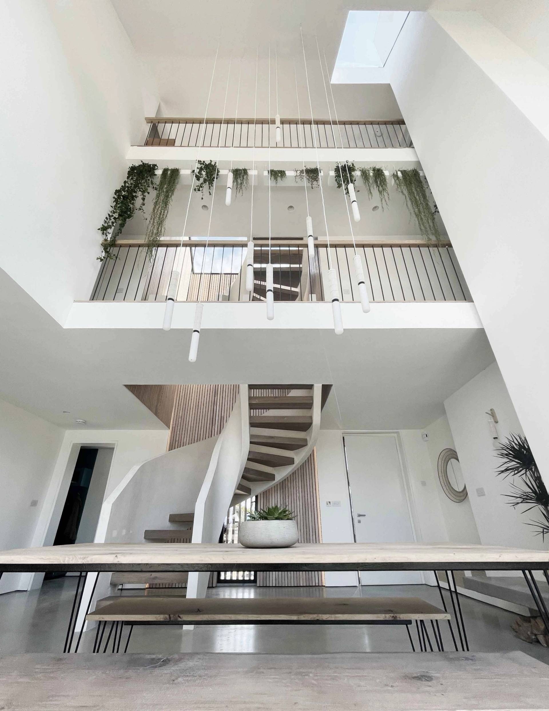 Wide view of a double-height dining room looking up to an upper mezzanine walkway with trailing indoor plants, Love Locations PO18.