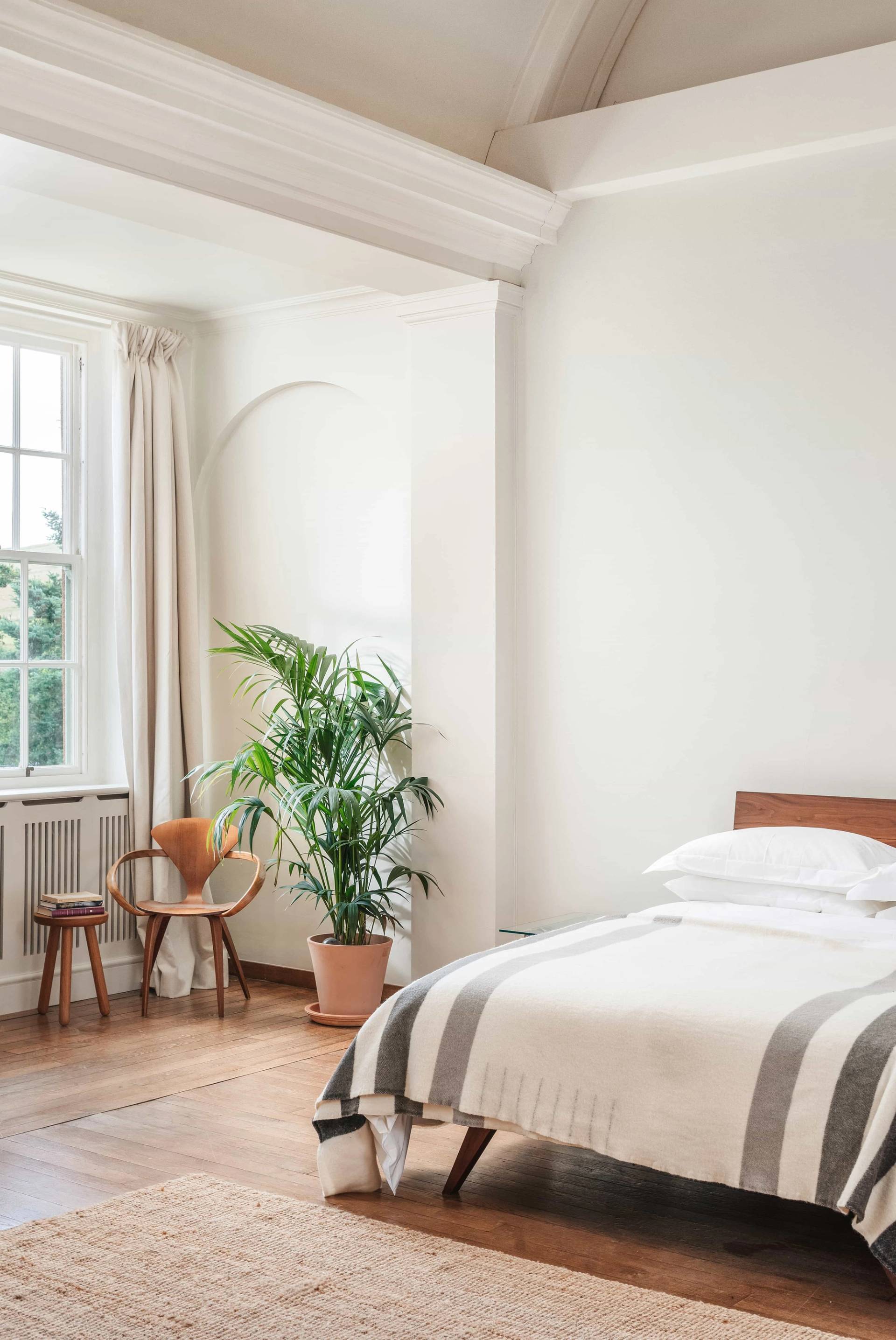 Airy secondary bedroom photoshoot setting with neutral decor and tall windows via Love Locations.