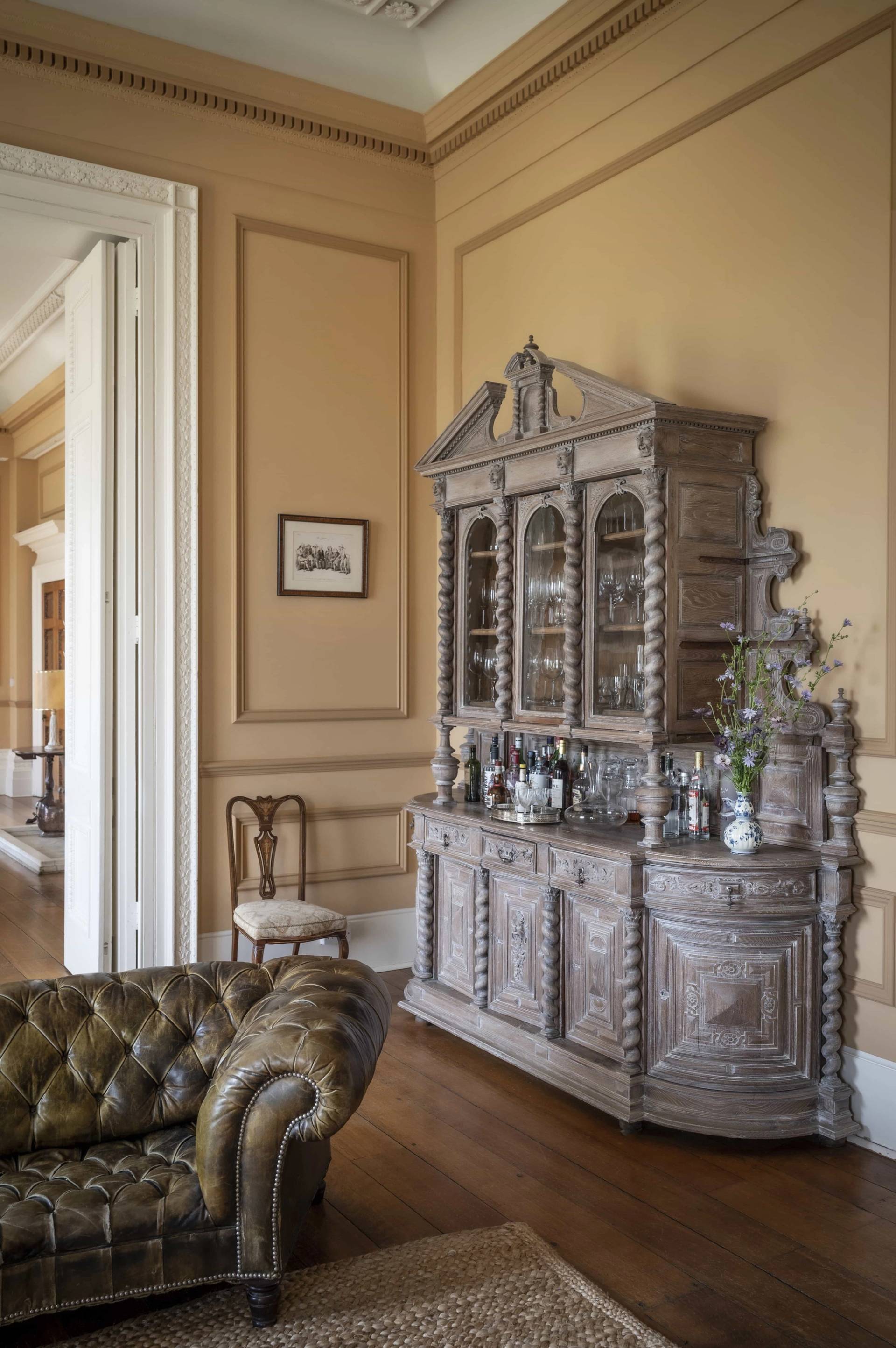 Carved antique wooden sideboard display unit set against ochre wall moulding in a Victorian country home, ideal for antique catalog features, Love Locations.