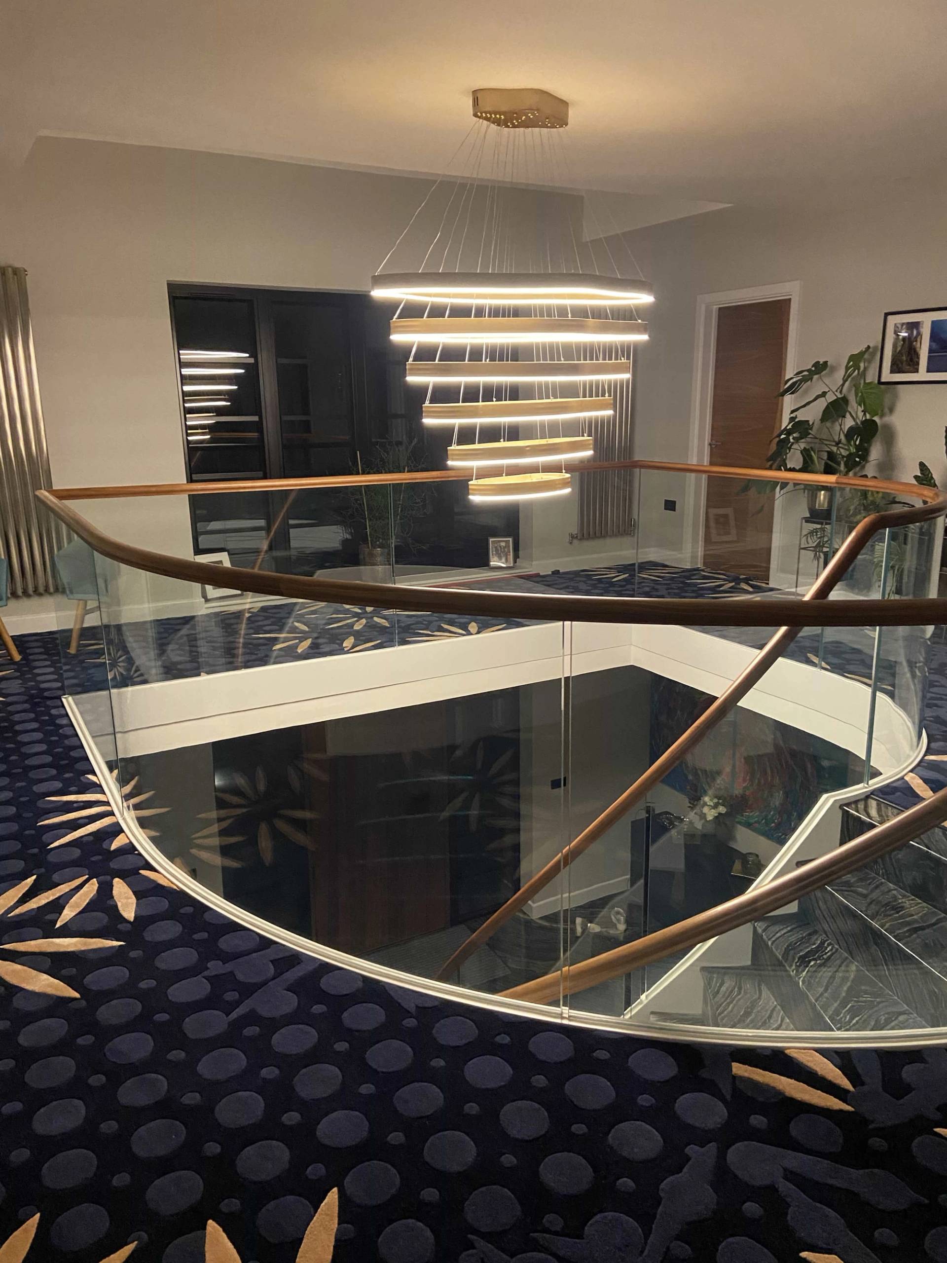 Galleried landing looking down into an entrance foyer through a geometric glass floor cutout, Love Locations CB2.