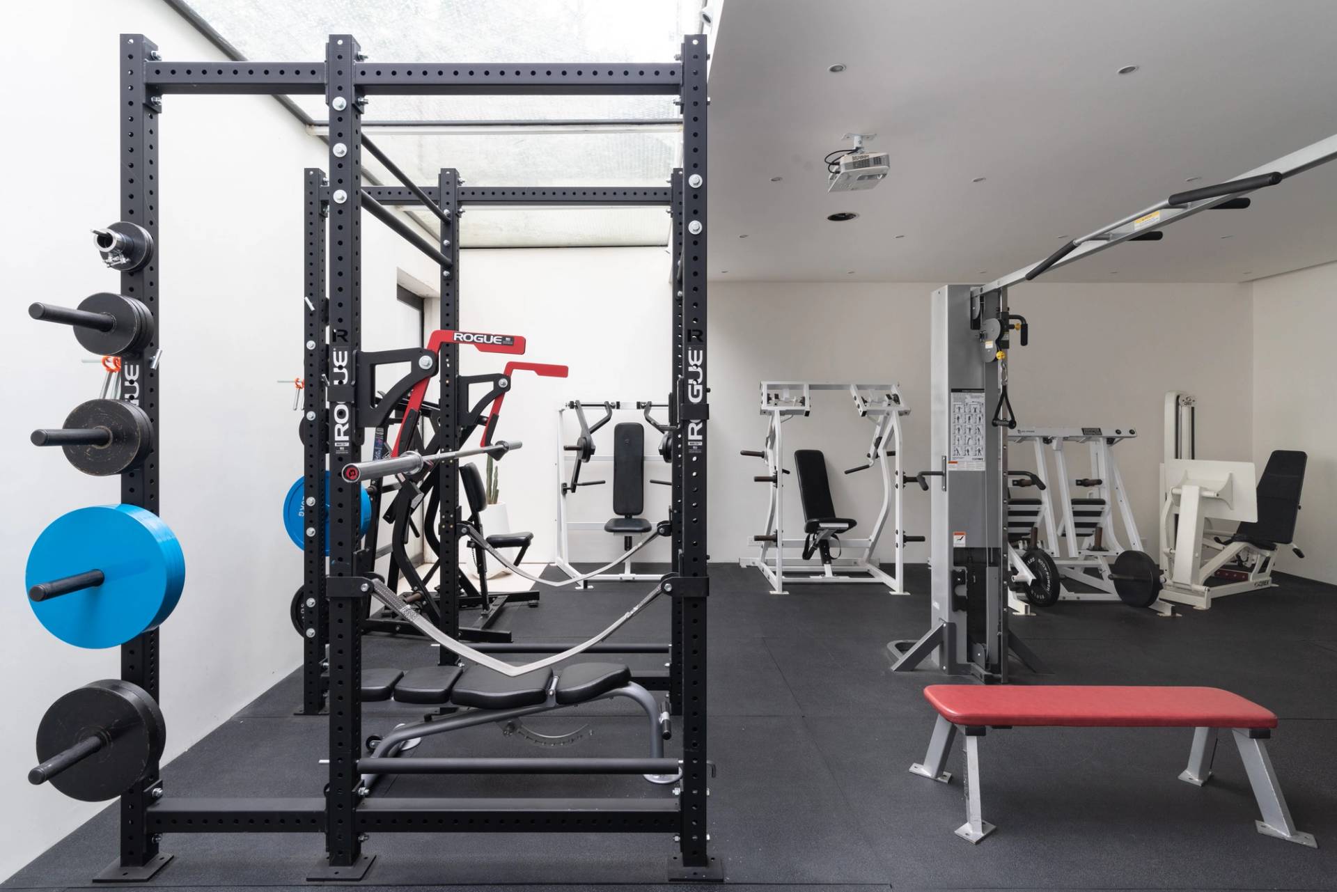Home gym setup with a heavy-duty weightlifting rack, pulley machines, and rubber gym floor matting, Love Locations SW6.