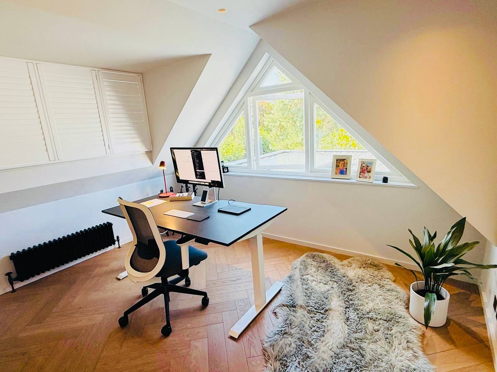 Attic home office workspace set beneath a triangular apex window with a standing desk, Love Locations TW11.