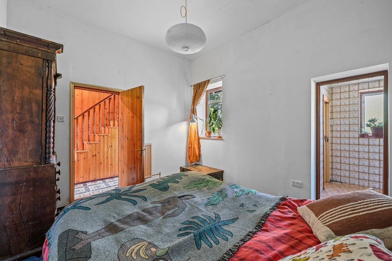Bedroom view showing a wood-panelled doorway opening into a carpeted stairwell passage, Love Locations E7.