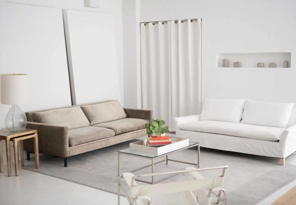Cozy contemporary seating vignette featuring cream sofas and a glass coffee table in a New York loft studio, Love Locations NY 10011.