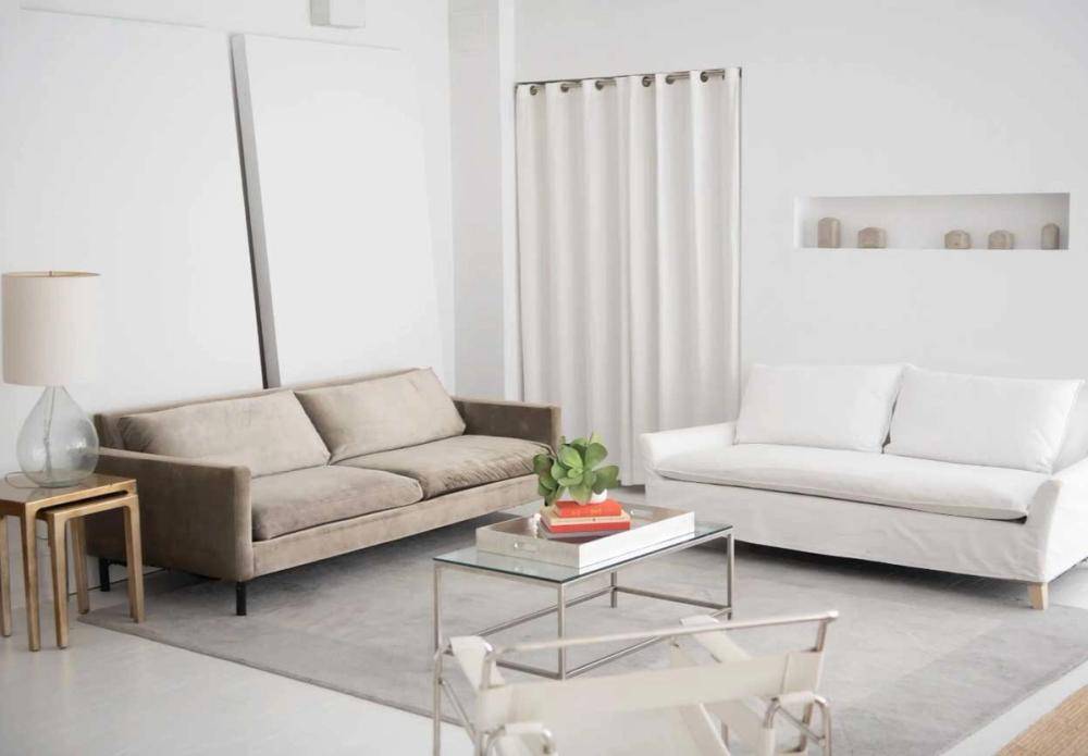Cozy contemporary seating vignette featuring cream sofas and a glass coffee table in a New York loft studio, Love Locations NY 10011.