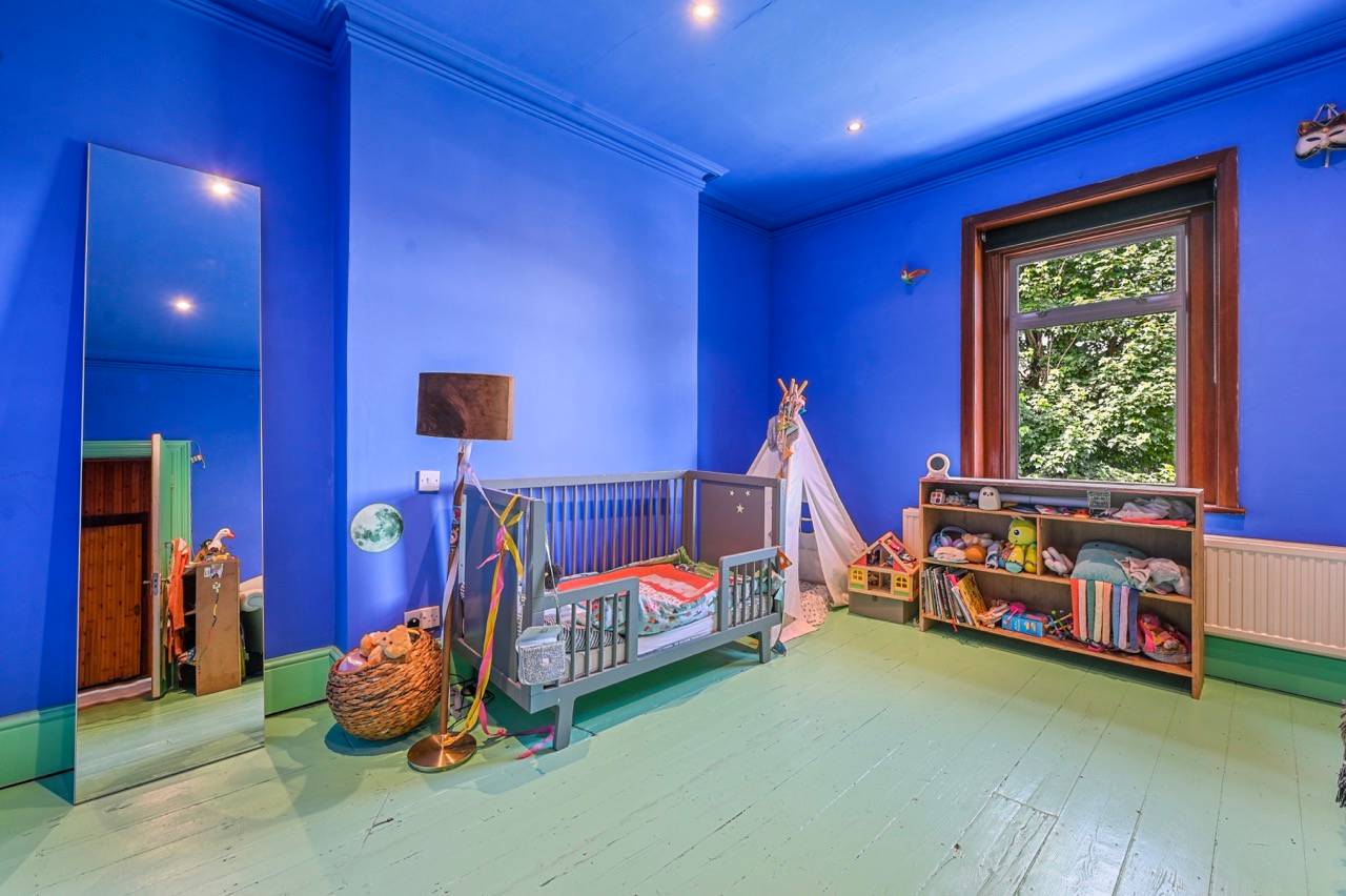 Vibrant royal blue painted kids bedroom or playroom featuring green painted floorboards, Love Locations.