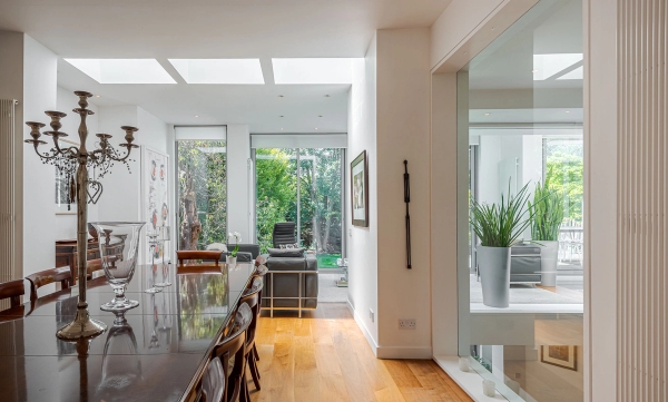 Architectural open-plan dining area featuring warm wooden floors and expansive floor-to-ceiling glass patio doors, ideal for furniture lookbooks, Love Locations W4.