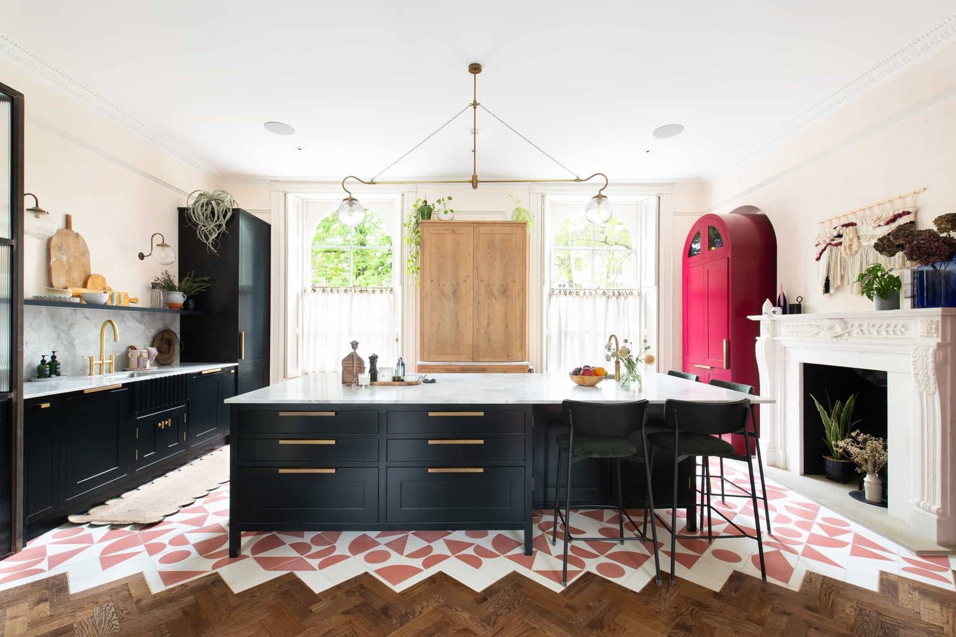 Modern open-plan kitchen in Camberwell, SE5 with black island, brass accents, marble worktops, and red accent cabinets via Love Locations.