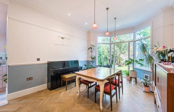 Traditional dining room shoot location featuring an elegant upright black piano and extensive garden view glazing, Love Locations.