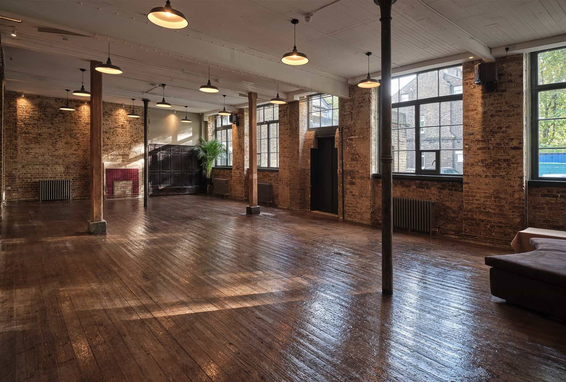 Wide industrial hall room with exposed brickwork, wooden columns, and industrial pendant lights in Shoreditch, Love Locations E2.