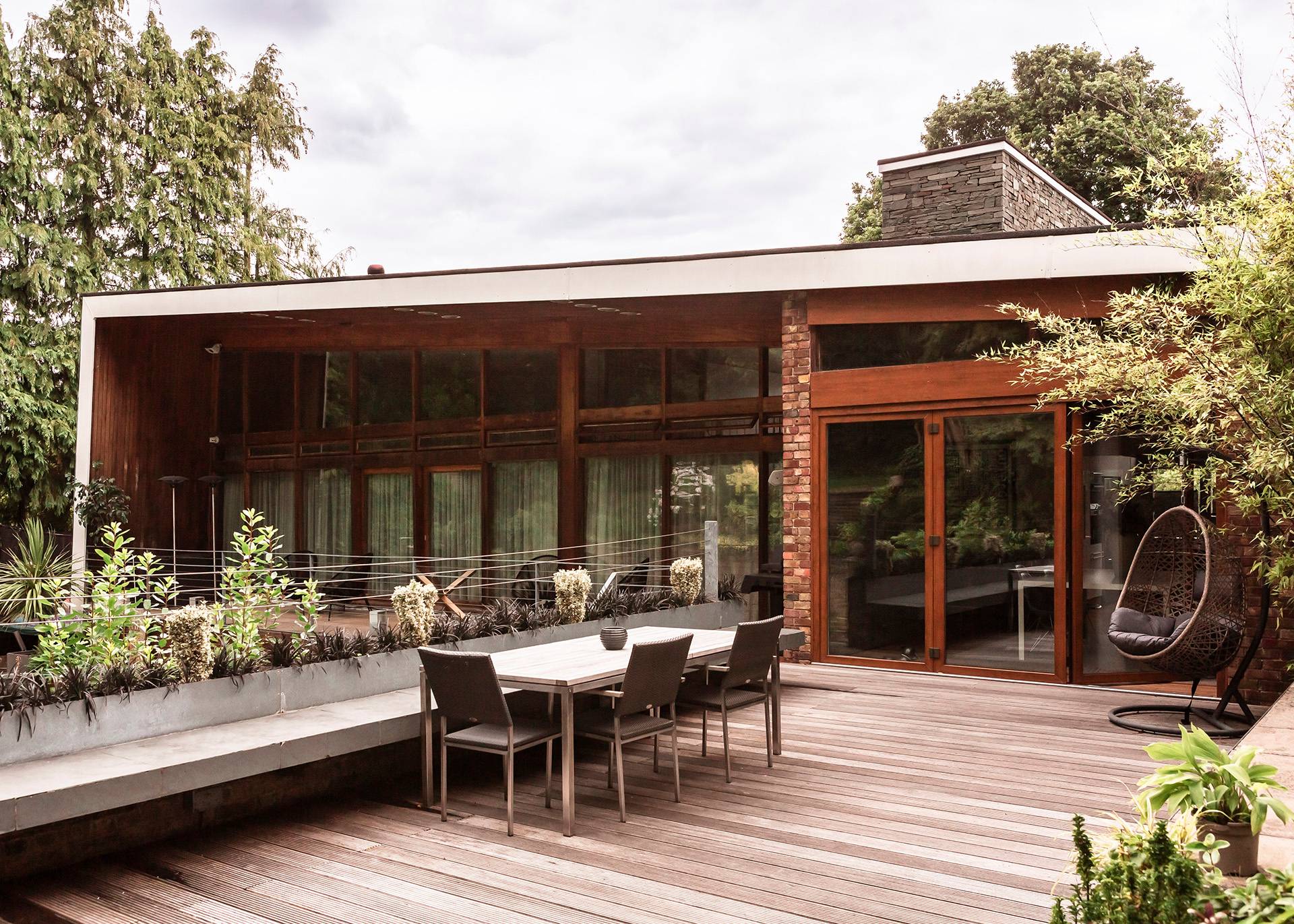 Large wooden balcony deck furnished with an outdoor dining table, perfect for summer lifestyle and fashion advertising via Love Locations.