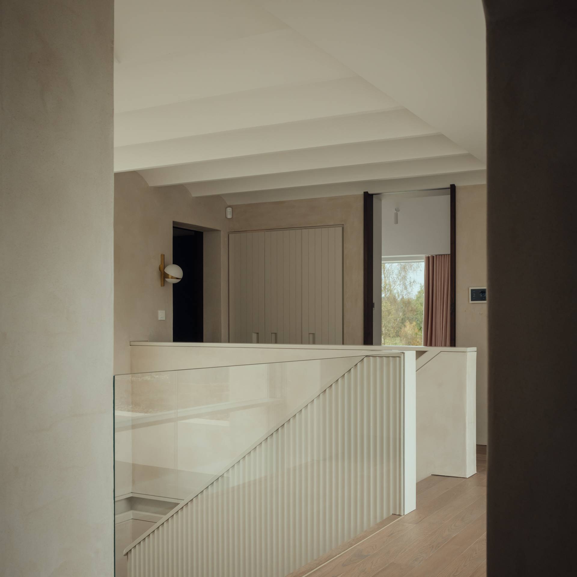 Upper floor glass mezzanine landing overlook with fluted panel walls in a modern Stockbridge countryside home, Love Locations SO20.