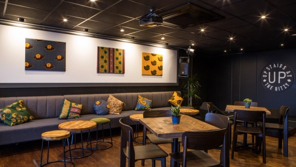 Cozy banquette seating area featuring patterned cushions, dark timber tables, and retro wall art at The Ritzy event space in Brixton, Love Locations SW2.
