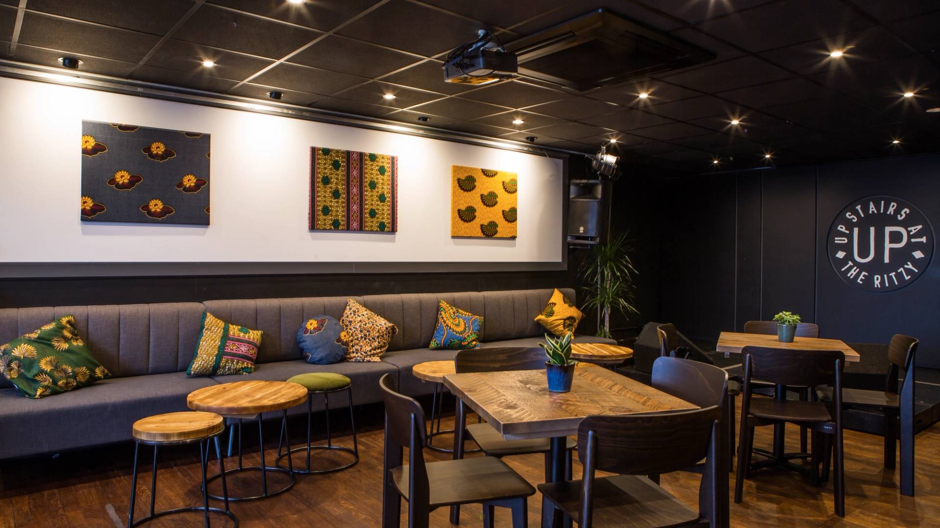 Cozy banquette seating area featuring patterned cushions, dark timber tables, and retro wall art at The Ritzy event space in Brixton, Love Locations SW2.