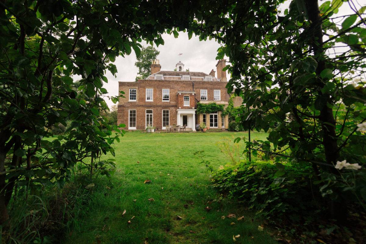 Framed garden perspective looking through tree foliage at a grand Georgian estate house, Love Locations SE15.