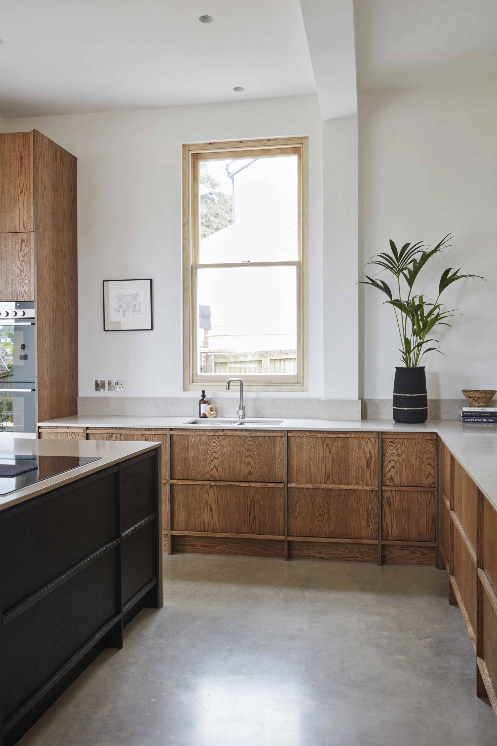 Spacious kitchen layout featuring rich wood cabinets, sash window, and polished concrete flooring, Love Locations.