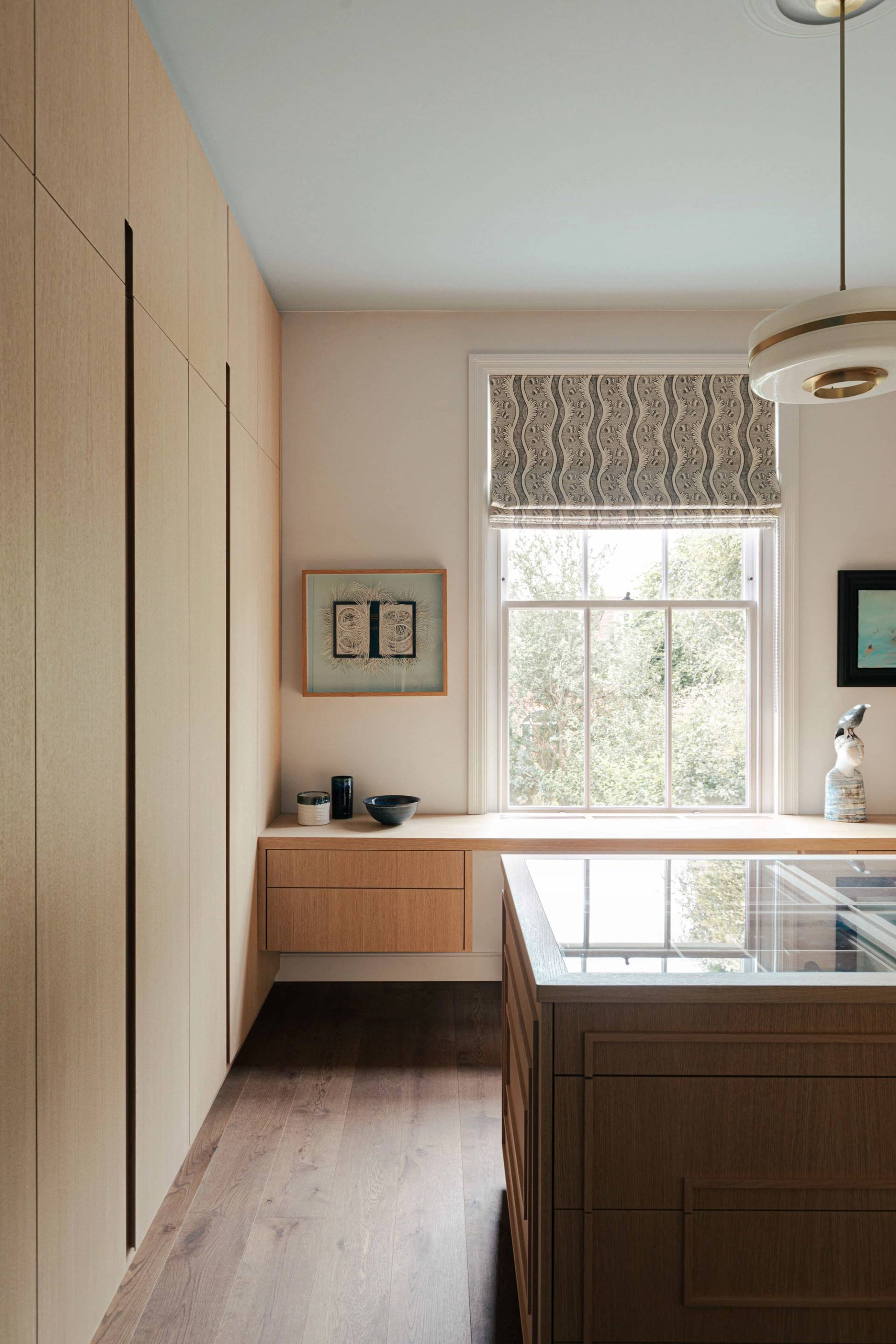 Bespoke dressing room setup with light oak wardrobes, island counter, and sash window views, Love Locations.