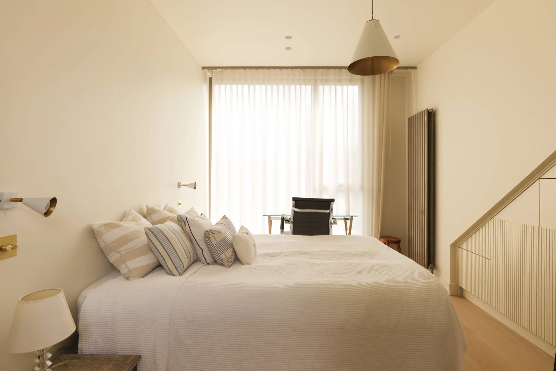 Bright master bedroom film location in Clapham South SW11 with neutral linens, large window, and minimalist decor from Love Locations.