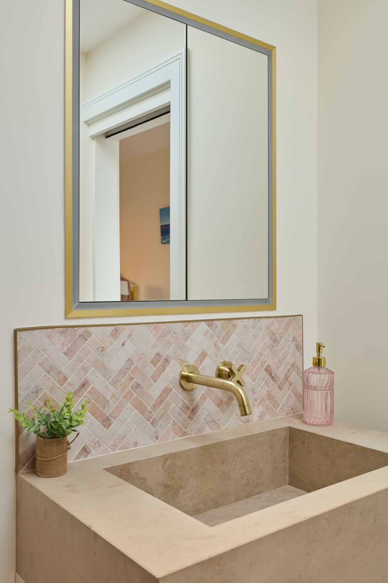 Close-up detail of a pink chevron tile splashback with gold brass tap and white marble basin, Love Locations.