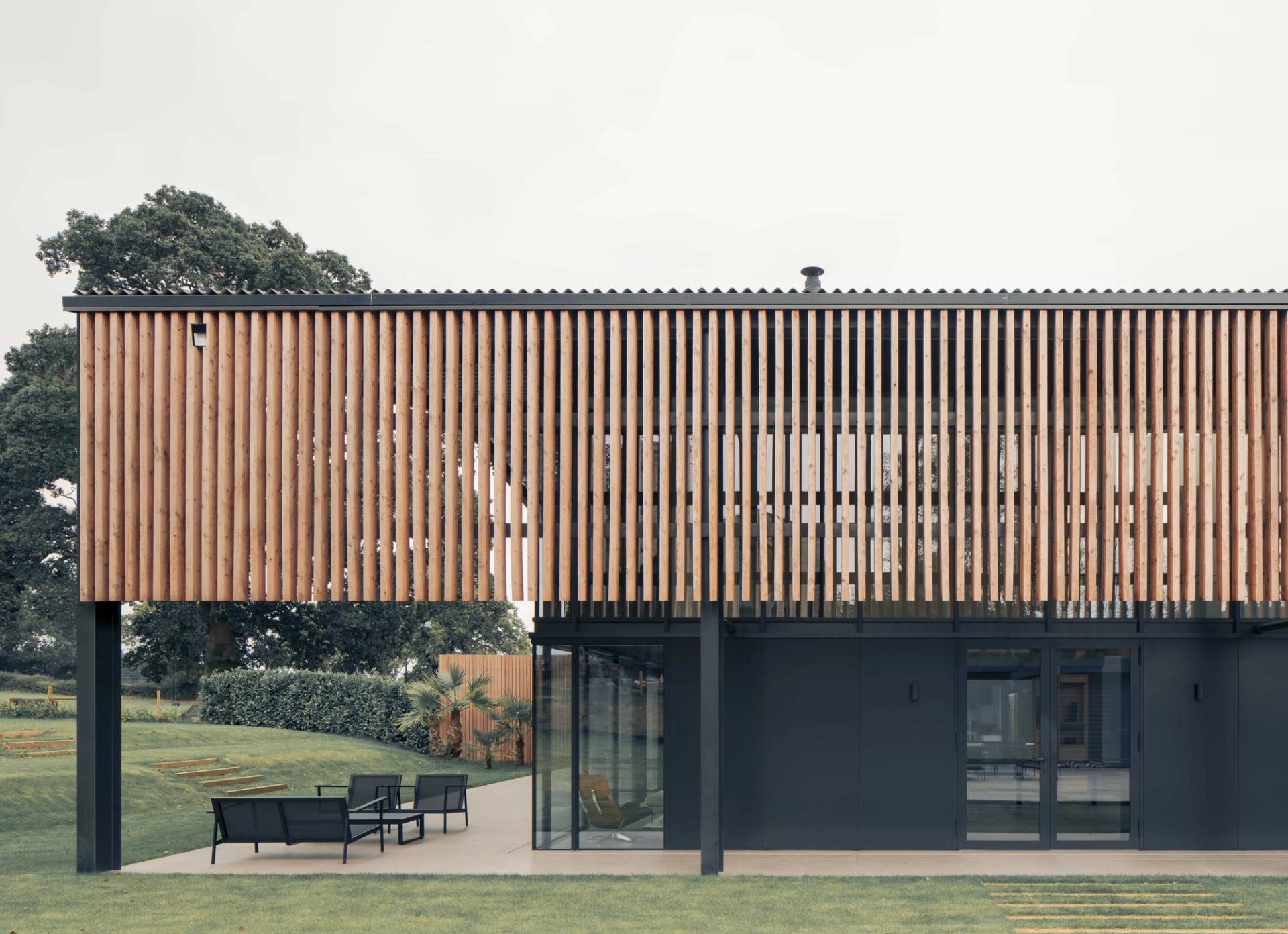 Contemporary timber-slat clad exterior facade set over a modern black glass ground floor, ideal for luxury automotive ads, Love Locations NR9.