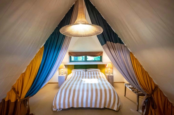 Charming attic loft bedroom built under a tented fabric canopy ceiling with striped bedding, excellent for creative fashion lookbooks, Love Locations.