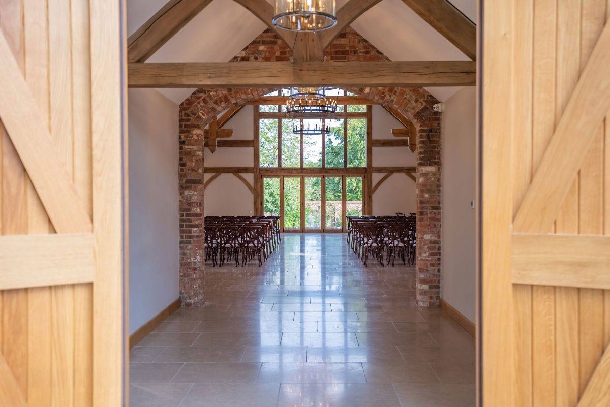 Rustic yet elegant barn wedding ceremony venue with polished floors and brick accents, listed on Love Locations, Haywards Heath.