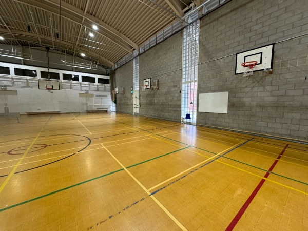 Love Locations modern secondary school sports hall Cockfosters EN4: Secondary indoor training court with clean concrete block walls and professional basketball backboards, ideal for fitness ads.