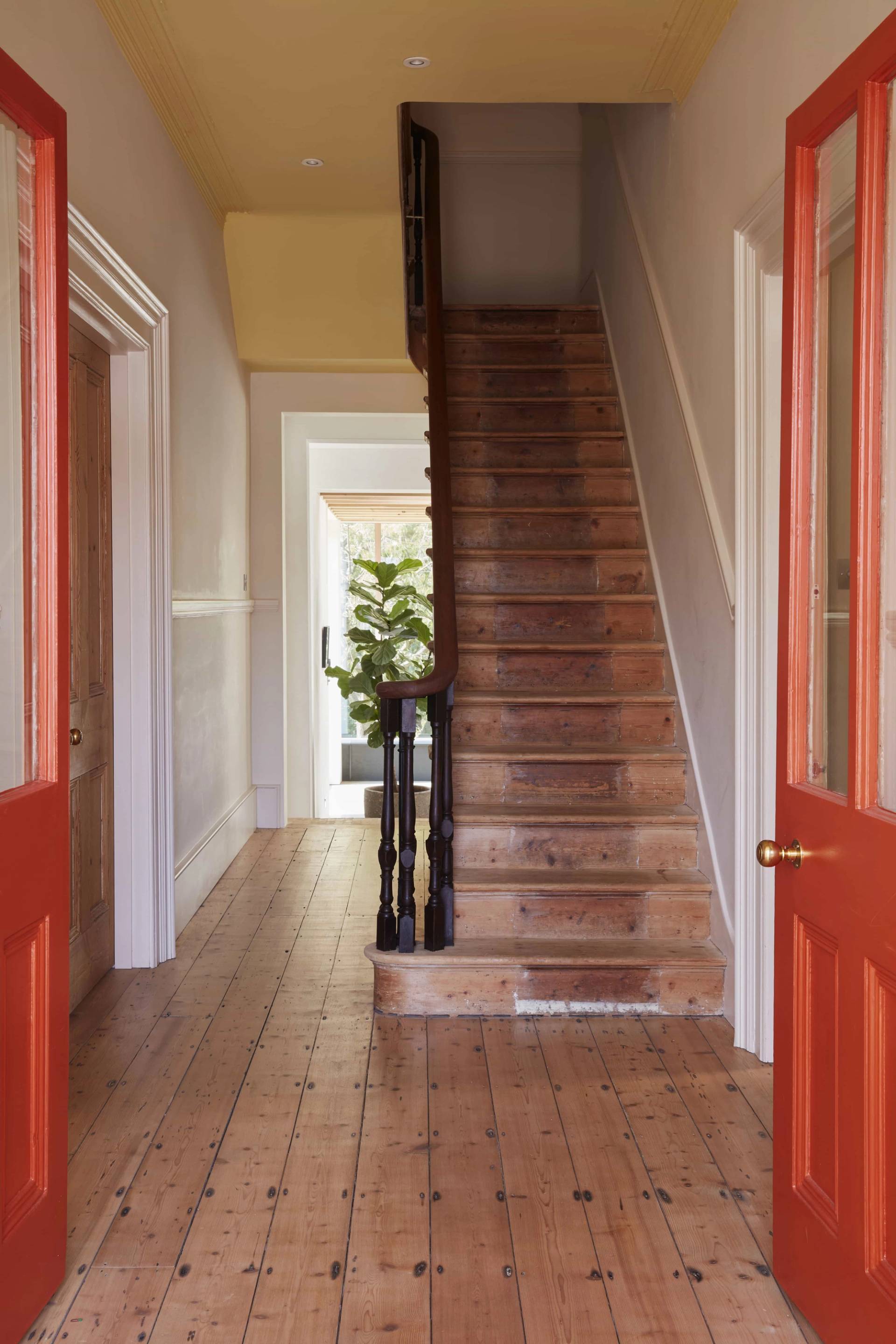 Grand hallway transition featuring a wooden staircase and contrasting vibrant orange double doors, ideal for creative brand backdrops, Love Locations TN34.